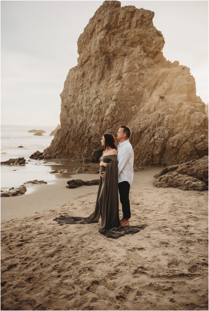 Couple during maternity photos at El Matador Beach in Malibu, CA during sunset