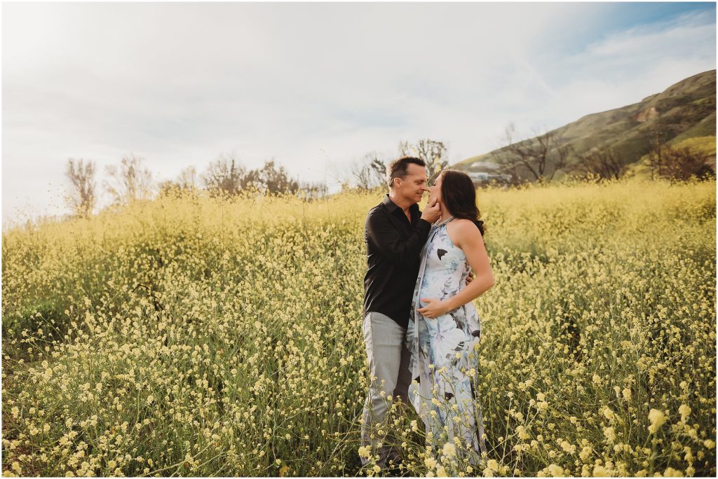 Couple during maternity photos at El Matador Beach in Malibu, CA during sunset in wildflowers